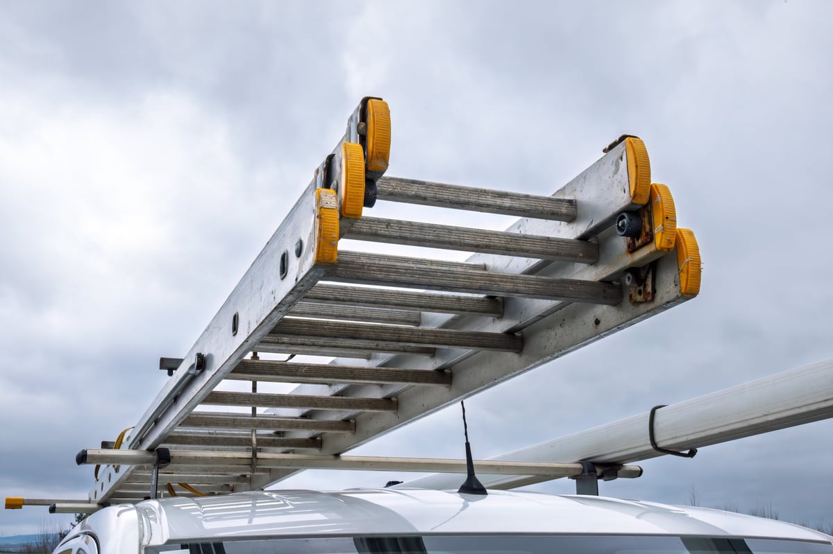 An extension ladder secured to a contractor van roof rack
